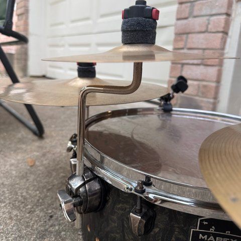 A knurled Z-shaped arm rising from the floor tom’s leg mount and holding a small cymbal.
