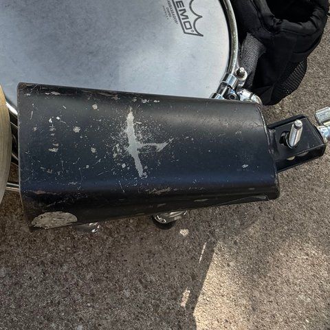 A worn black cowbell mounted beside the snare.