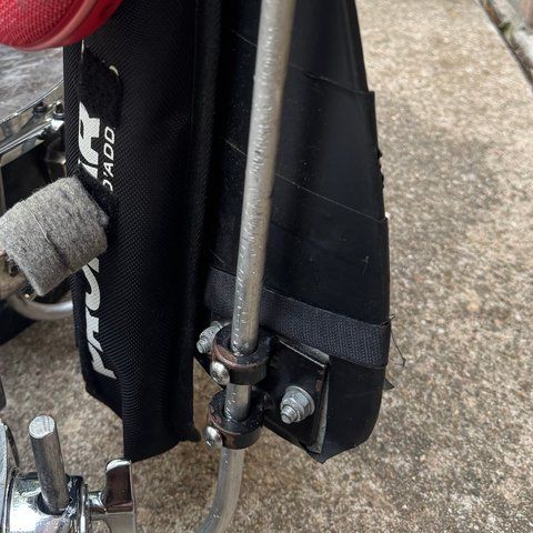 A plain aluminum rod bolted to the harness, bending down into a drum mount on the snare.