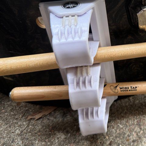 A white Yamaha clip holder on the floor-tom shell, holding two brushes.