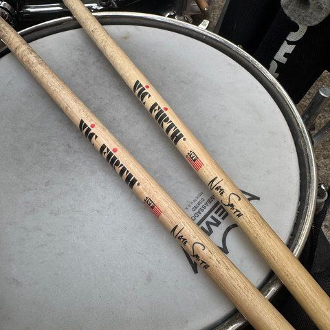 Two Vic Firth Nate Smith signature drumsticks lying across the snare head.